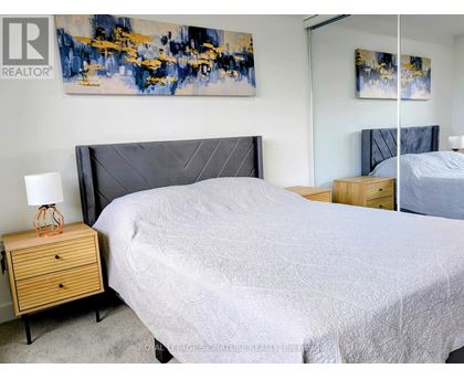 A bedroom with a large bed and a painting on the wall.