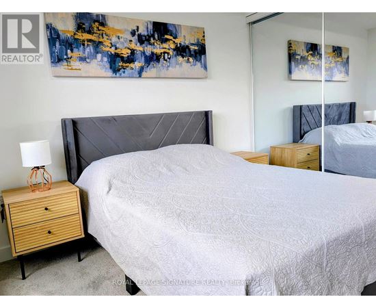 A bedroom with a large bed and a painting on the wall.