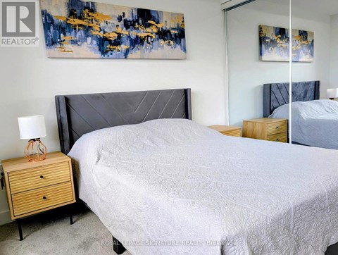 A bedroom with a large bed and a painting on the wall.