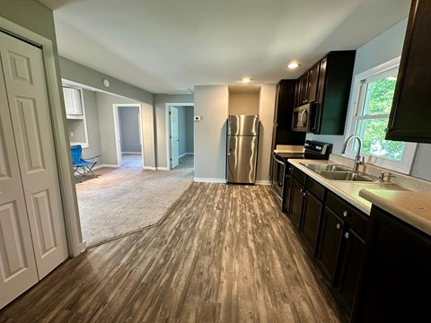 A kitchen with dark wood cabinets and a stainless steel refrigerator.