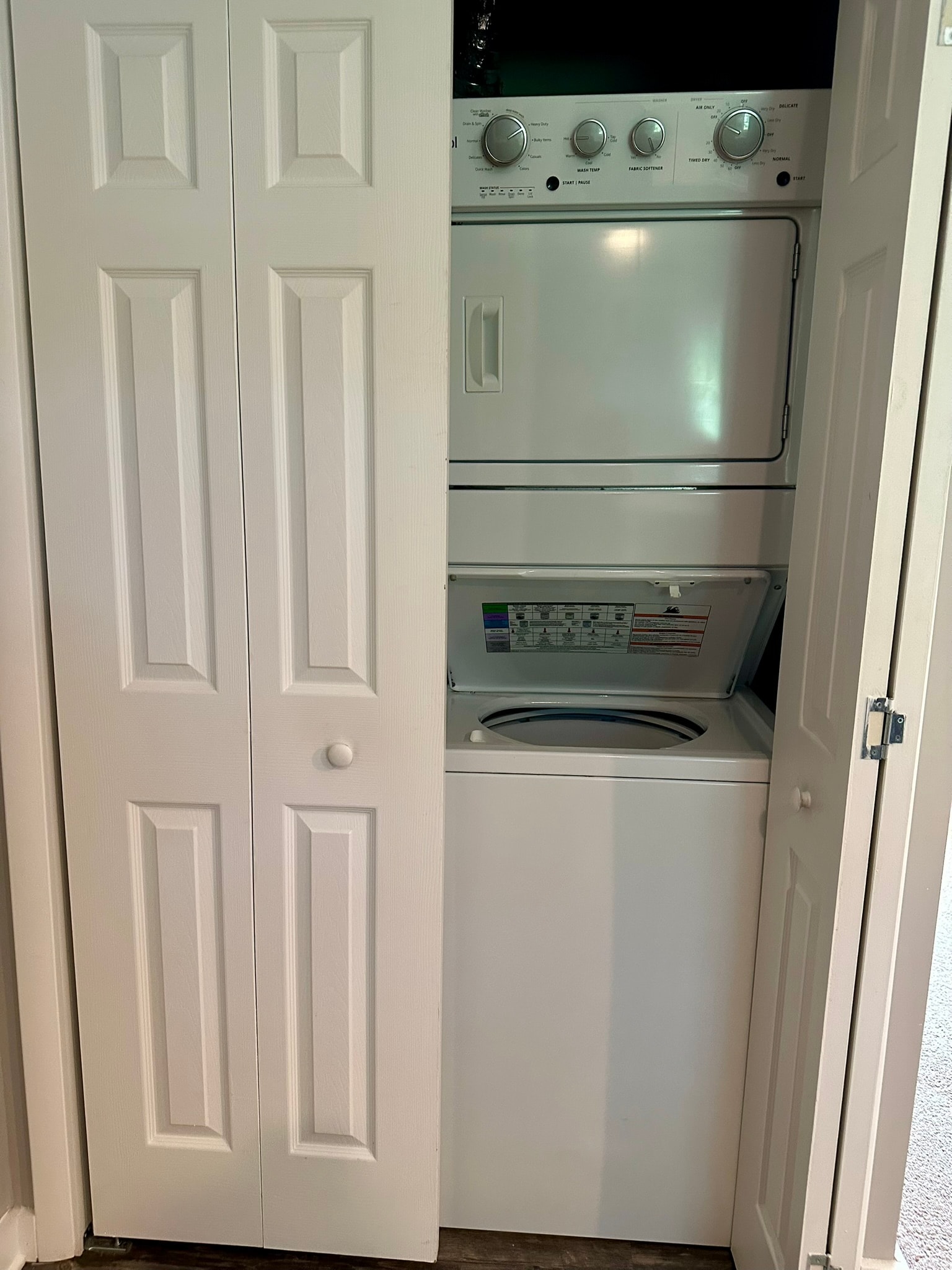 A white door is open to a small kitchen with a stove and oven.