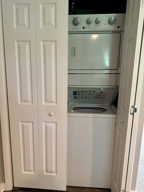A white door is open to a small kitchen with a stove and oven.