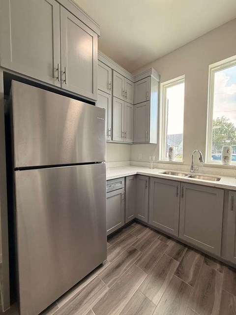 A kitchen with a stainless steel refrigerator and wooden flooring.
