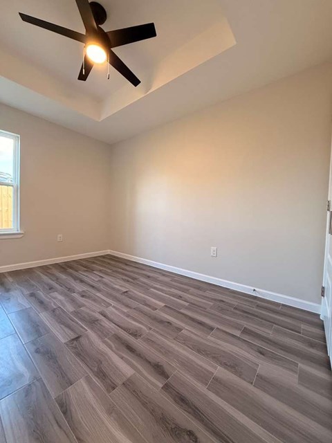 A room with a ceiling fan and wooden flooring.