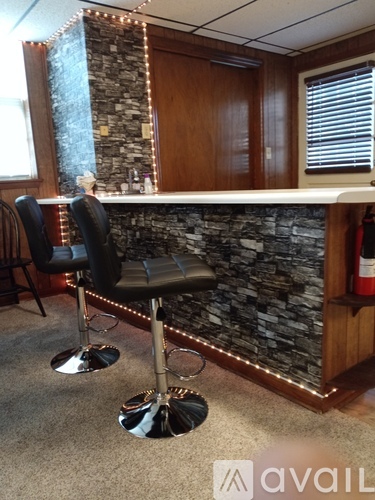 A bar area with a stone wall and two chairs.