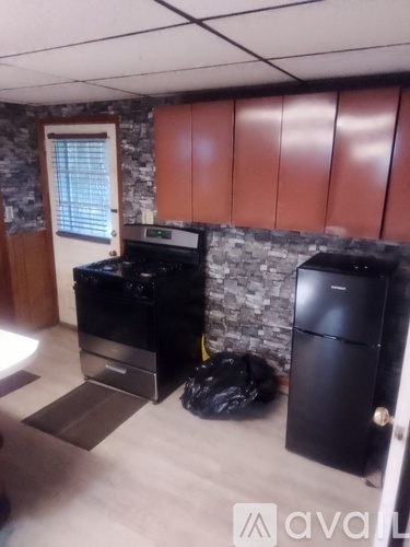 A black fridge and freezer in a kitchen with wooden cabinets.