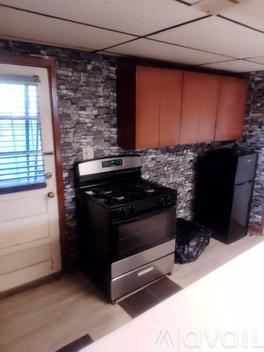 A kitchen with a stove and a trash can.