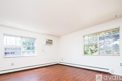 Empty room with wooden floor and two windows.