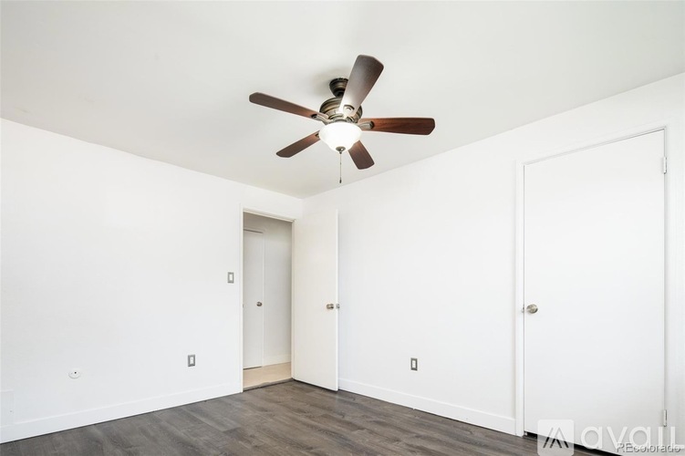 A room with a ceiling fan and two doors.