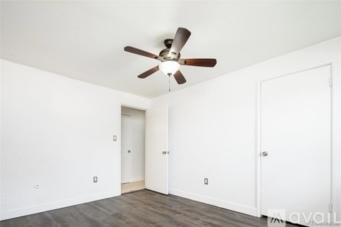 A room with a ceiling fan and two doors.