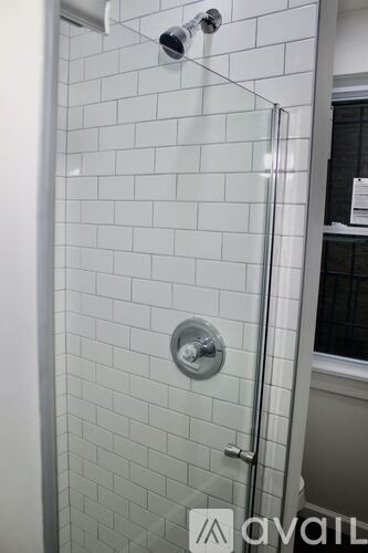 A white tiled shower with a glass door and a shower head.