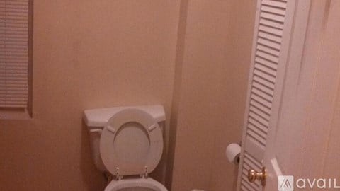 A white toilet is mounted on a wall next to a white door.