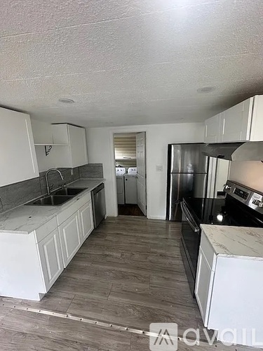 A kitchen with white cabinets and a grey floor.