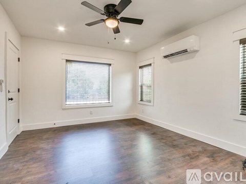 A spacious room with a ceiling fan and a window with blinds.