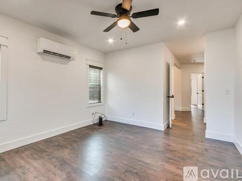 A spacious room with a ceiling fan and wooden flooring.
