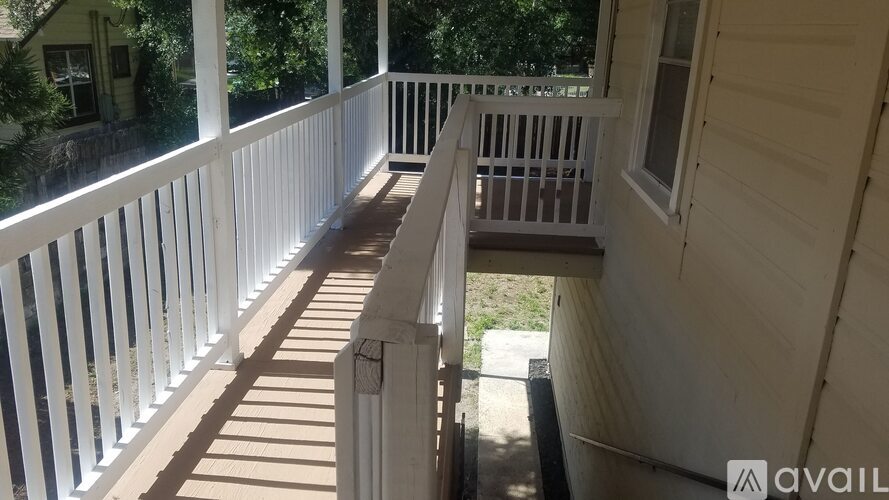 A white porch with a wooden floor and railings.