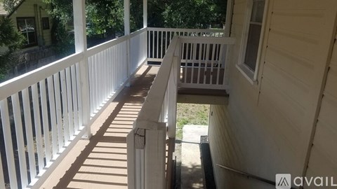 A white porch with a wooden floor and railings.