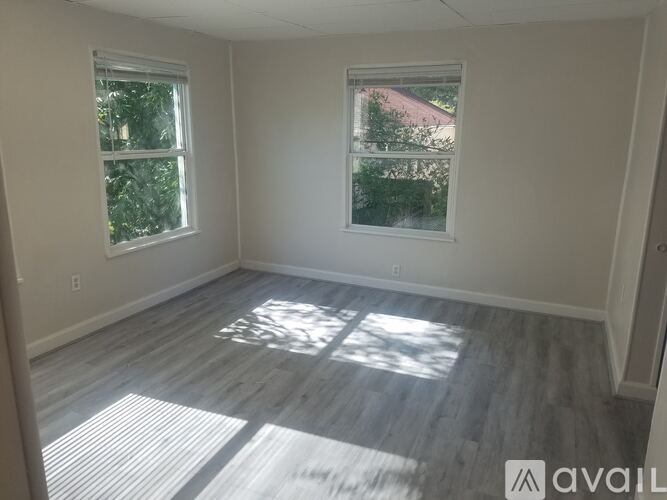 A room with two windows and wooden flooring.