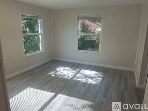 A room with two windows and wooden flooring.