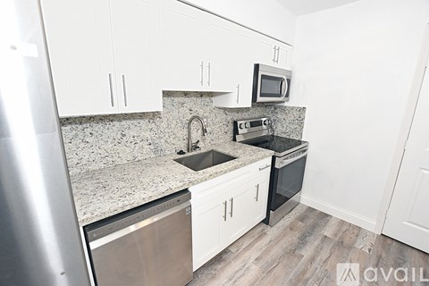 A kitchen with white cabinets and a granite countertop.