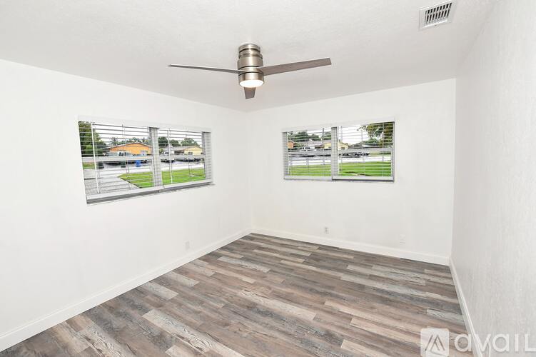 A room with a ceiling fan and two windows with blinds.