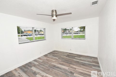 A room with a ceiling fan and two windows with blinds.