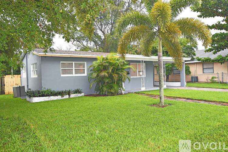 A house with a grey exterior and a palm tree in front.