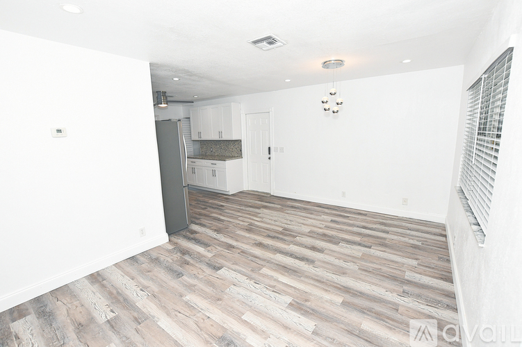 A kitchen area with a refrigerator, cabinets, and a clock on the wall.