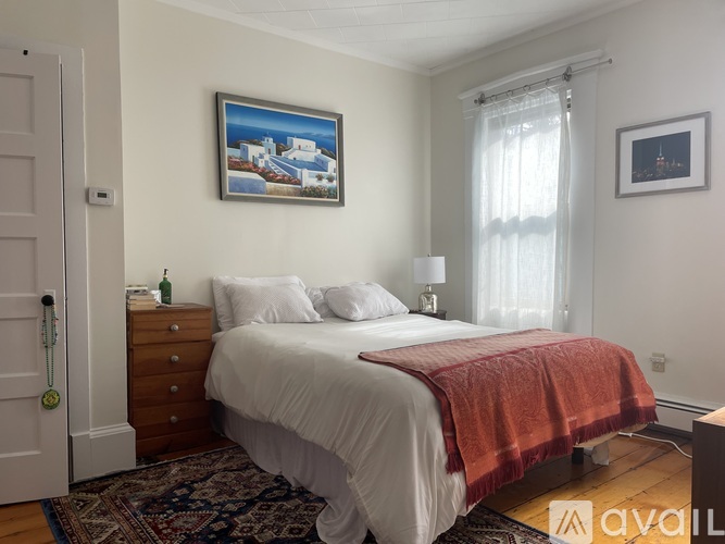 A bedroom with a bed, a dresser, a painting, and a window.