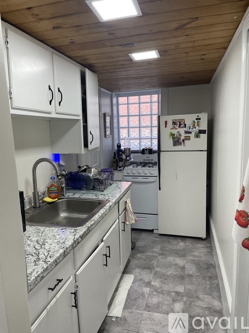 A kitchen with white cabinets and a wooden ceiling.