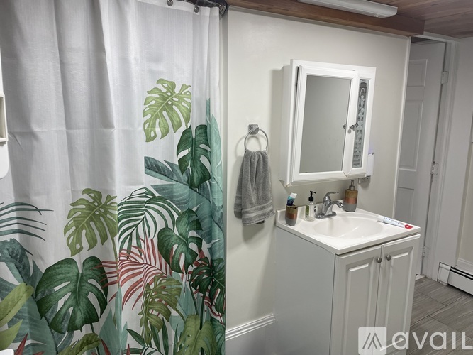 A bathroom with a white sink and a shower curtain with a leaf pattern.