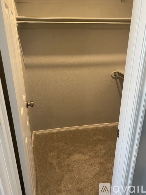 A small, empty room with a carpeted floor and a white door.