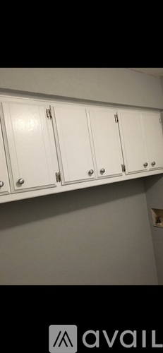 A white cabinet with silver handles is mounted on a wall.