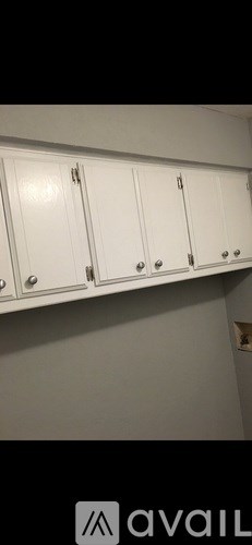 A white cabinet with silver handles is mounted on a wall.