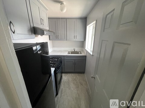A kitchen with a black fridge and a black stove top oven.