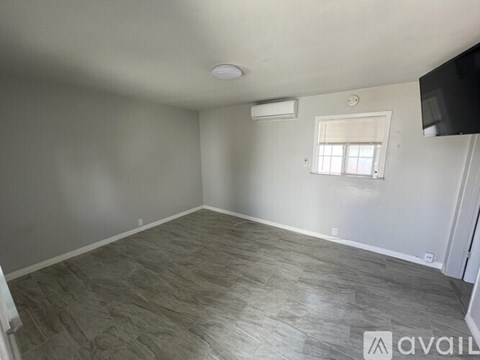 A spacious room with a window and a flat-screen TV mounted on the wall.