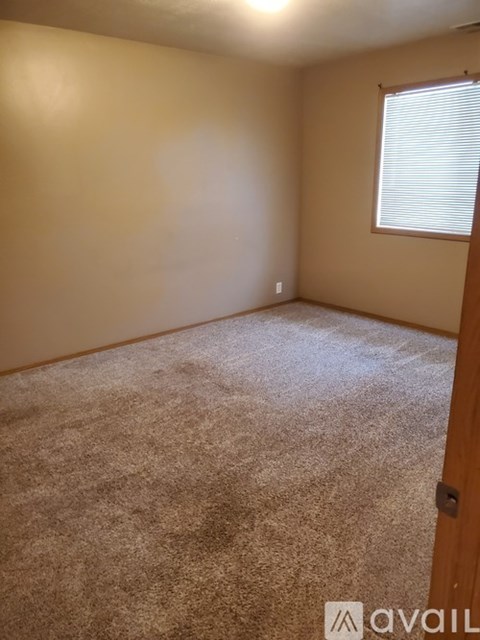A room with a carpeted floor and a window with blinds.