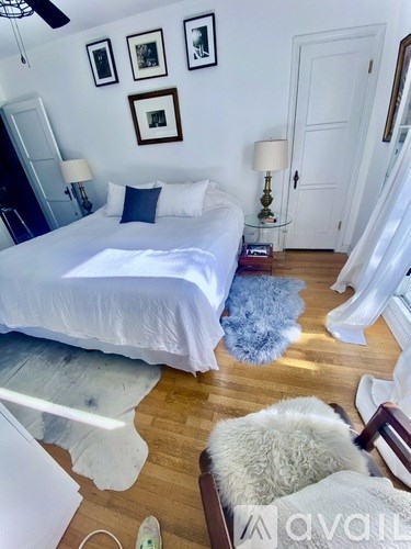 A bedroom with a white bed and a blue rug.