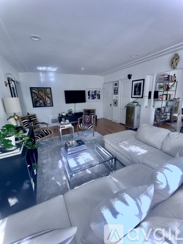 A living room with a white couch and a glass coffee table.