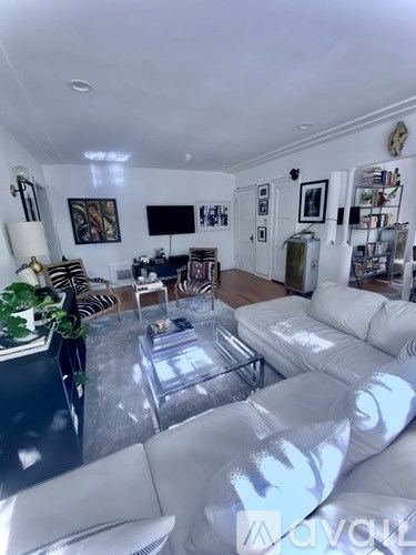 A living room with a white couch and a glass coffee table.