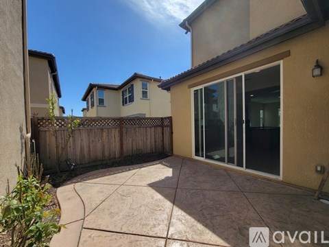 A patio area with a sliding glass door and a wooden fence.