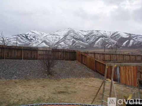 A snowy mountain range is in the background of a wooden fence.
