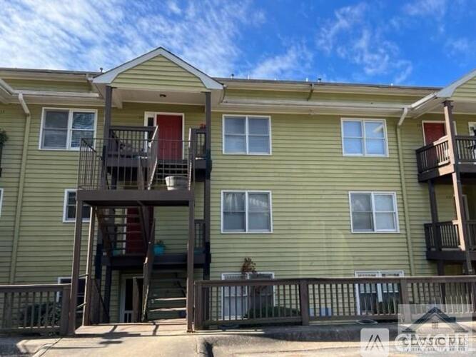 A two-story apartment building with a balcony and a red door.