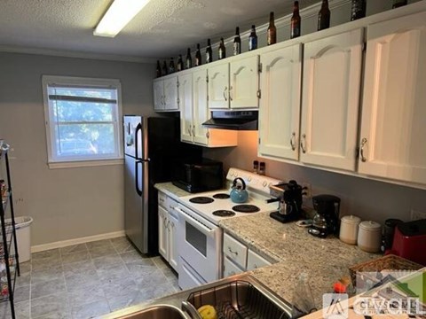 A kitchen with white cabinets and a black refrigerator.