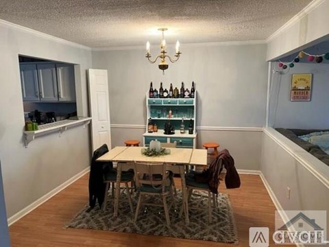 A dining area with a table surrounded by chairs and a wine rack on the wall.