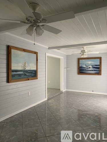 A room with a ceiling fan and two framed pictures on the wall.