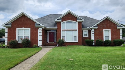 A red brick house with a front yard and a walkway leading to the front door.