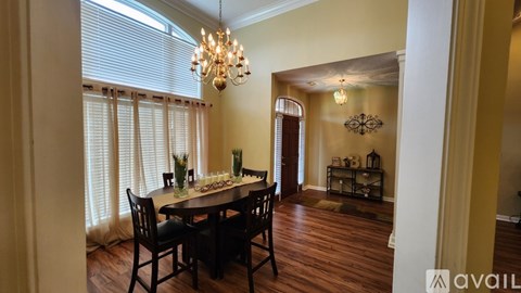 A dining room with a table set for six and a chandelier hanging from the ceiling.
