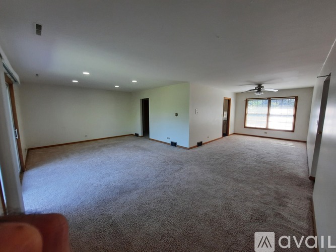 A spacious room with a carpeted floor and a ceiling fan.