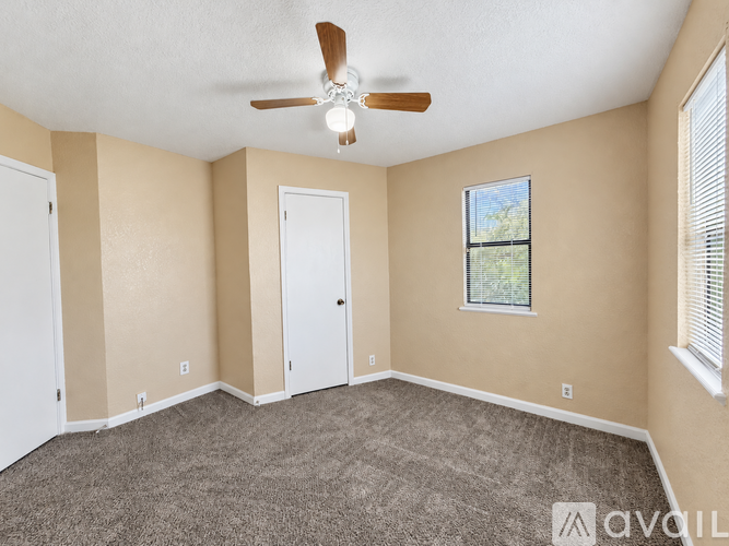 A room with a ceiling fan and a window with a view of trees.